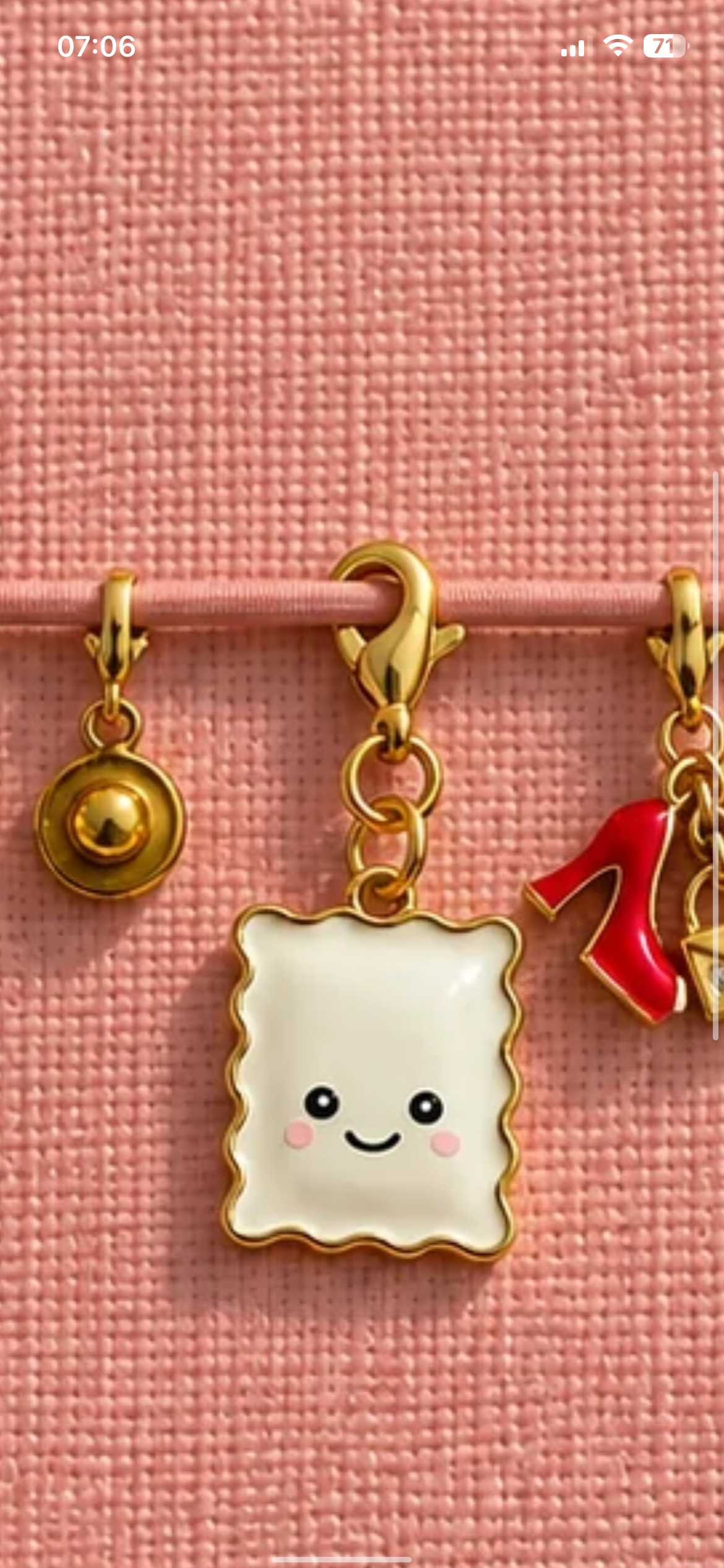 Le pendentif Raviole Coquette avec ses anneaux et son mousqueton sur un carnet rose